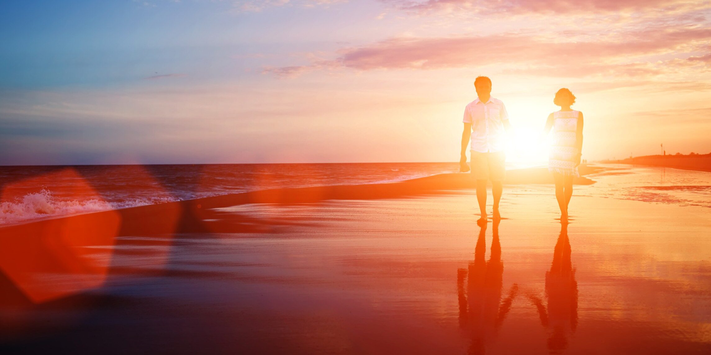 Romantic Sunset Stroll on the Beach A couple walking hand in hand on a beach during sunset, with the sun casting a warm glow on the sand and waves.